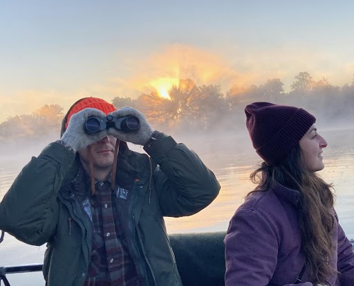 Kelsey and a person holding binoculars standing on a boat