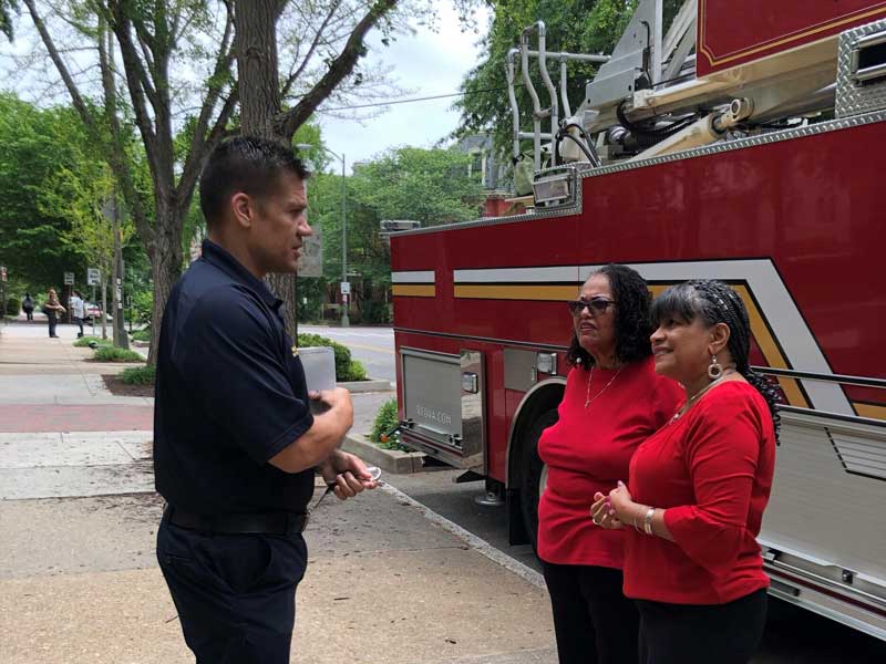 faye belgrave and anita nadal speak with Battalion Chief Bailey Martin of the Richmond Fire Department in front of a fire truck on campus